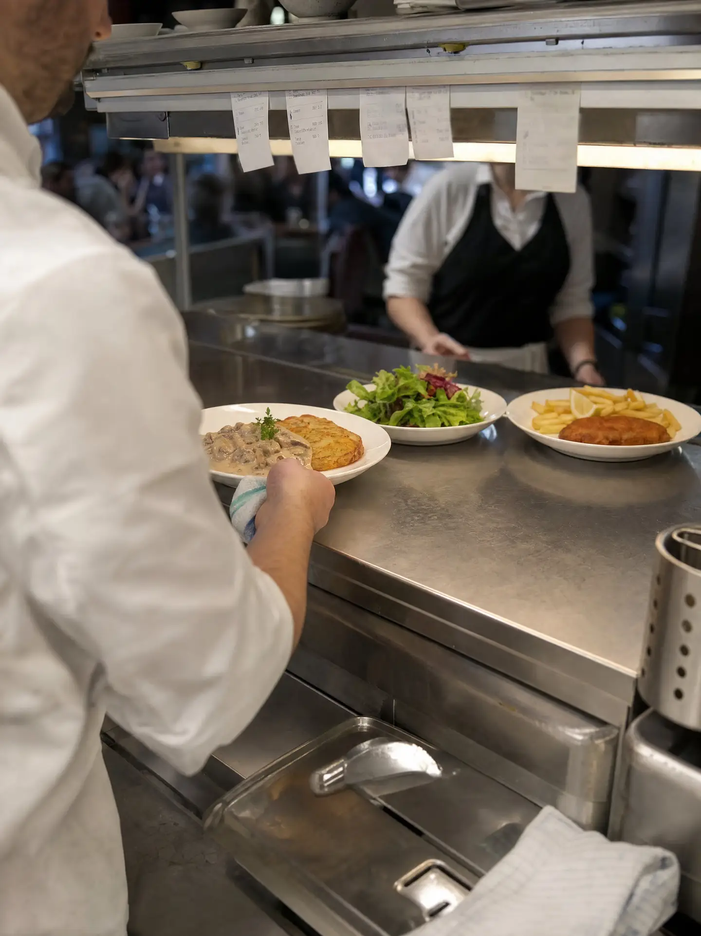 Durchreiche einer Restaurantküche: Geschnetzeltes mit Rösti, Salat und Schnitzel mit Pommes für den Service