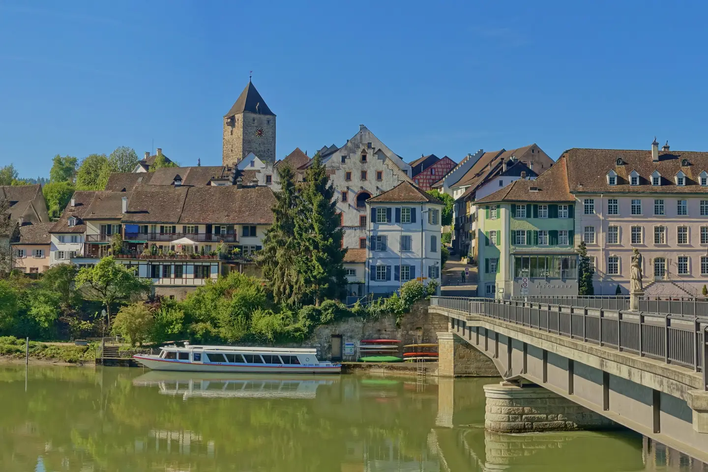 Kaiserstuhl AG vom Rhein aus: Altstadthäuser mit dem Oberen Turm, davor ein Kursschiff am Ufer und rechts die Rheinbrücke